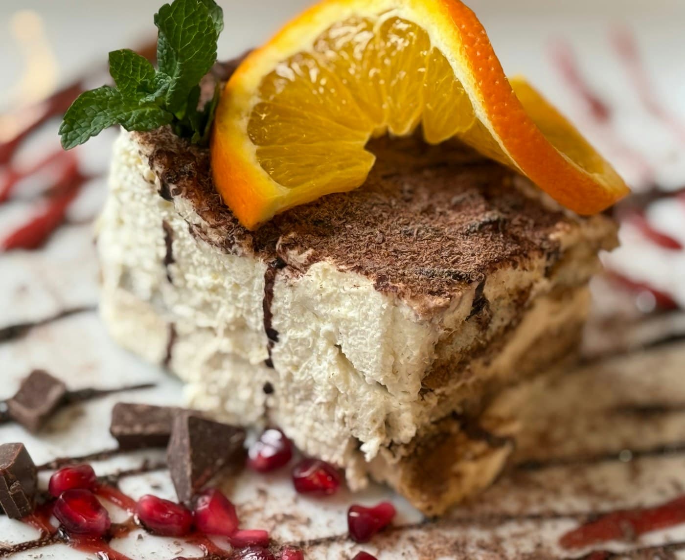 A Tiramisù plated with orange, mint, chocolate and pomegranate